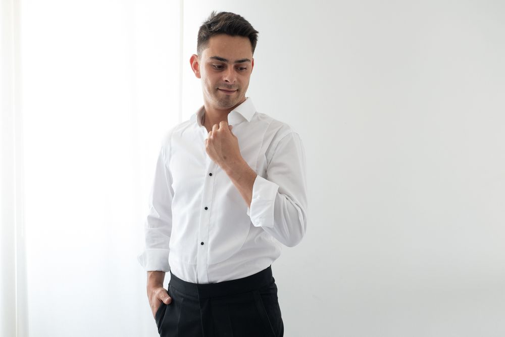 Well-dressed individual in a crisp white button-down shirt against white background.