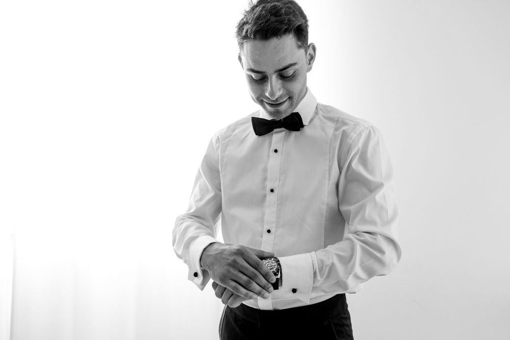 Black and white photo of person adjusting formal wear cuffs.