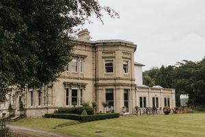 An image of Cleatham Hall with bay windows and manicured lawn under an overcast sky.