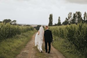 Couple walking down a scenic country path together on their wedding day at Cleatham Hall.