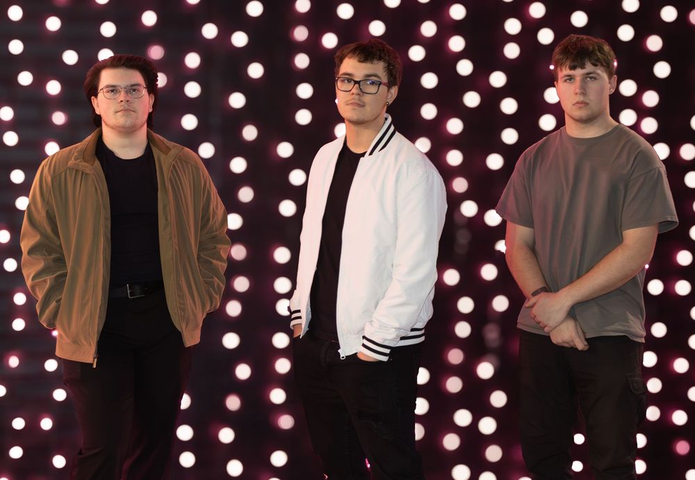 Several people posed against a dark background with white polka dot lighting.