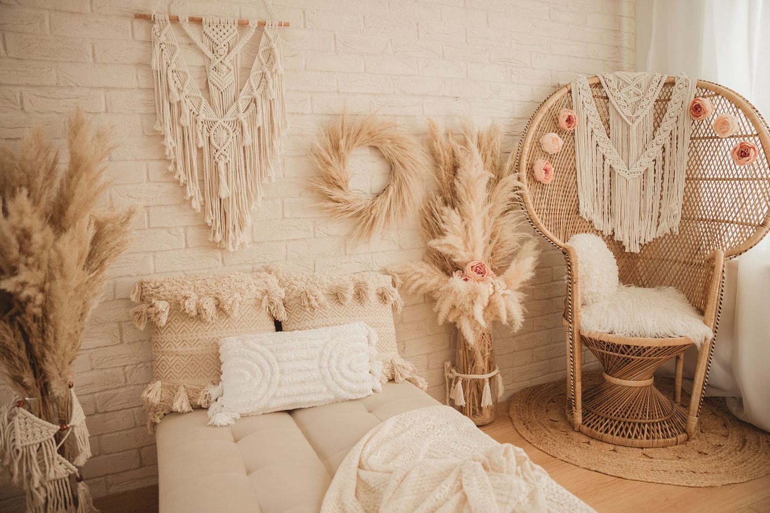 A cozy boho bedroom with macrame wall hangings, pampas grass, and a peacock chair in warm neutral tones.