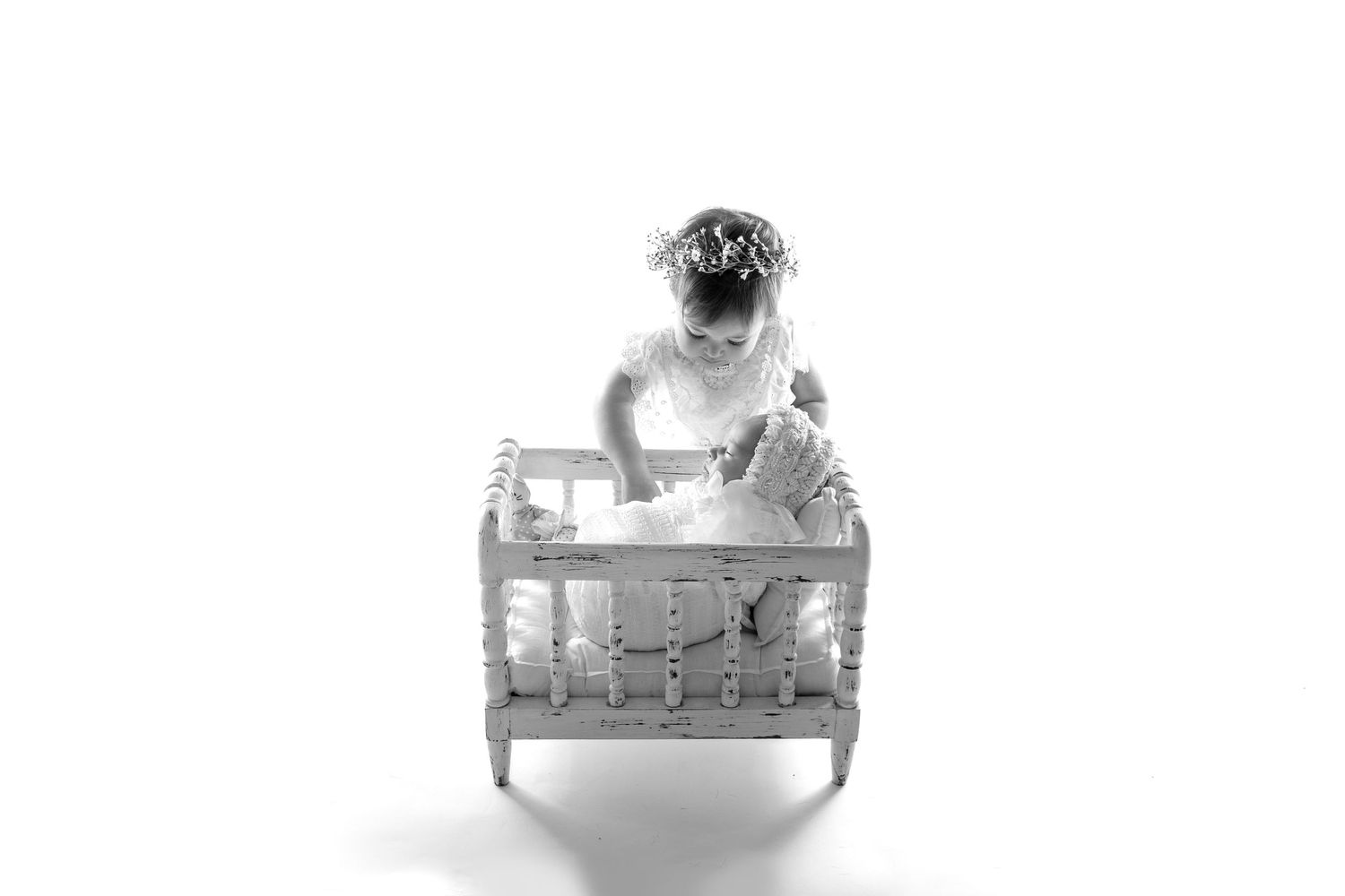 A black and white photograph shows a pug puppy sitting atop a clear glass or acrylic box in an artistic composition.