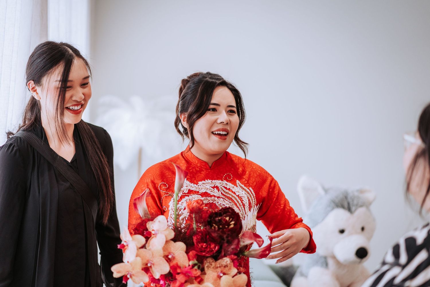 Wedding preparations show people in festive red attire and black clothing indoors with floral decorations.