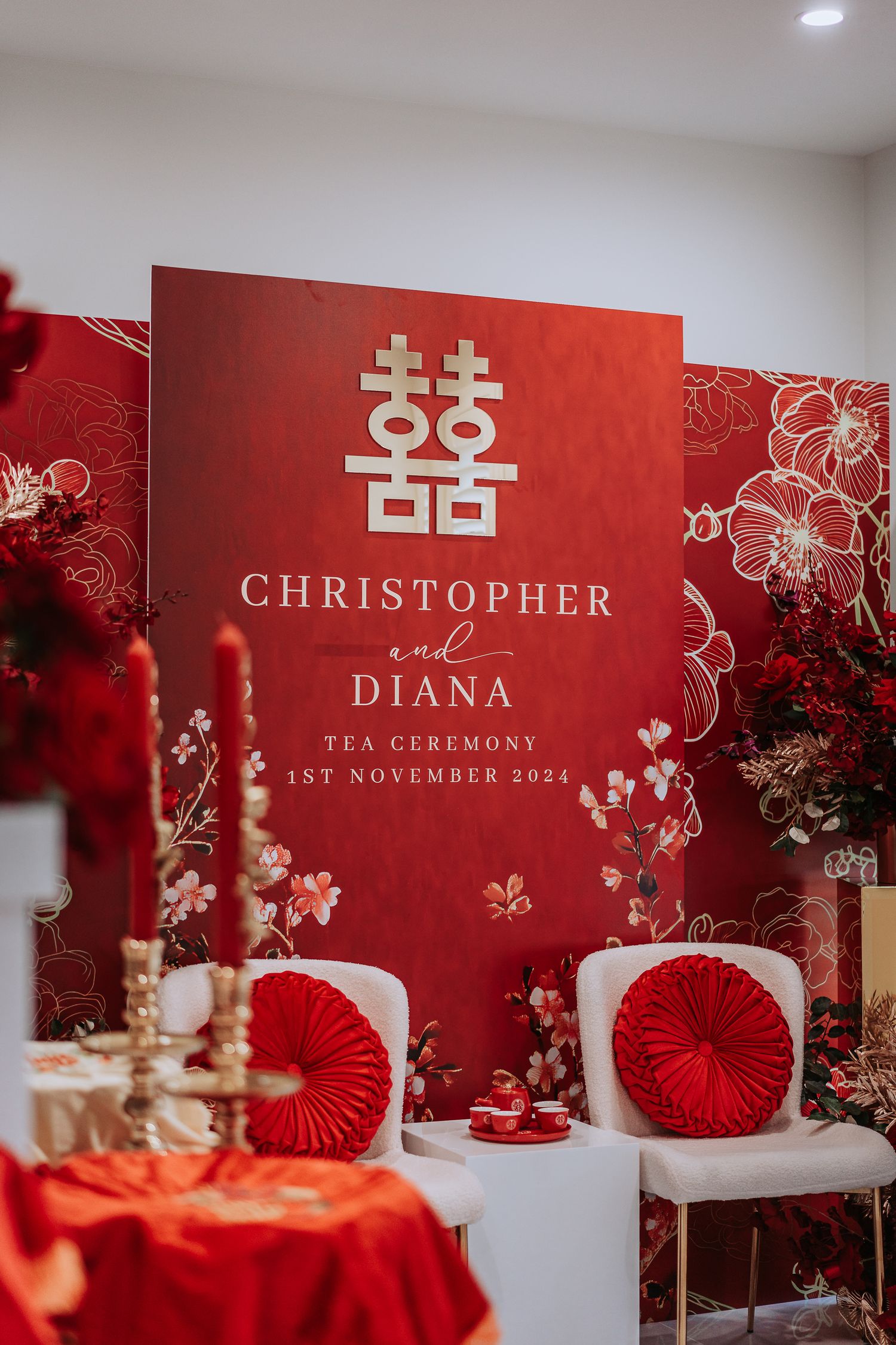 Red and gold Chinese wedding decor with double happiness symbol and floral arrangements.