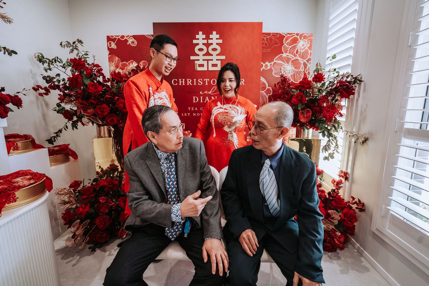 Traditional Chinese wedding scene with double happiness symbol and red floral decorations in background.