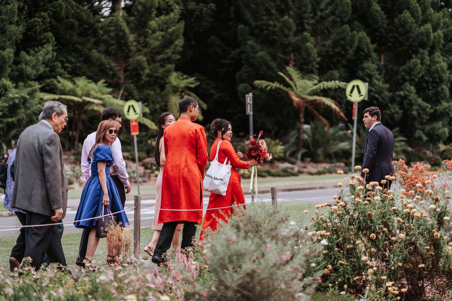 Group in formal attire gathering outdoors in a garden setting during a traditional celebration.