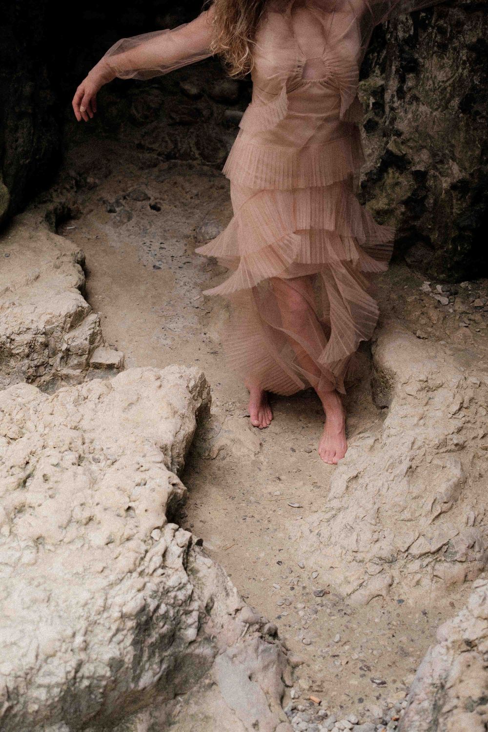 A flowing pink dress moves gracefully against limestone cliffs.