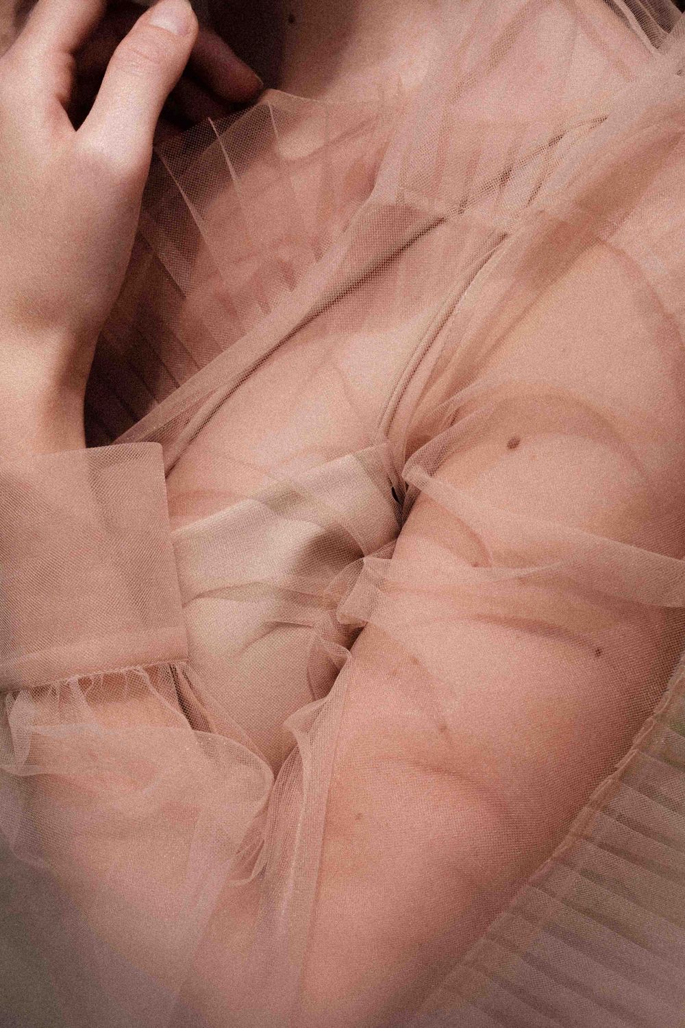 Close-up detail of nude-colored tulle fabric creating soft, romantic texture.