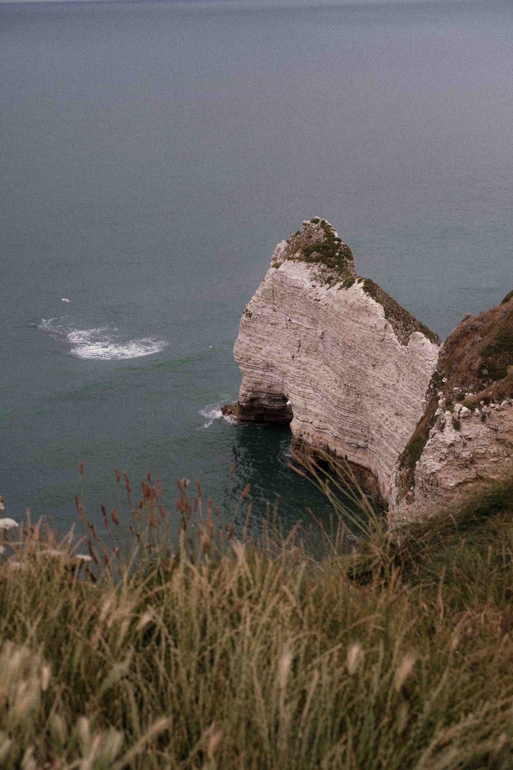 White chalk cliffs tower over the sea with waves crashing against rocky formations.