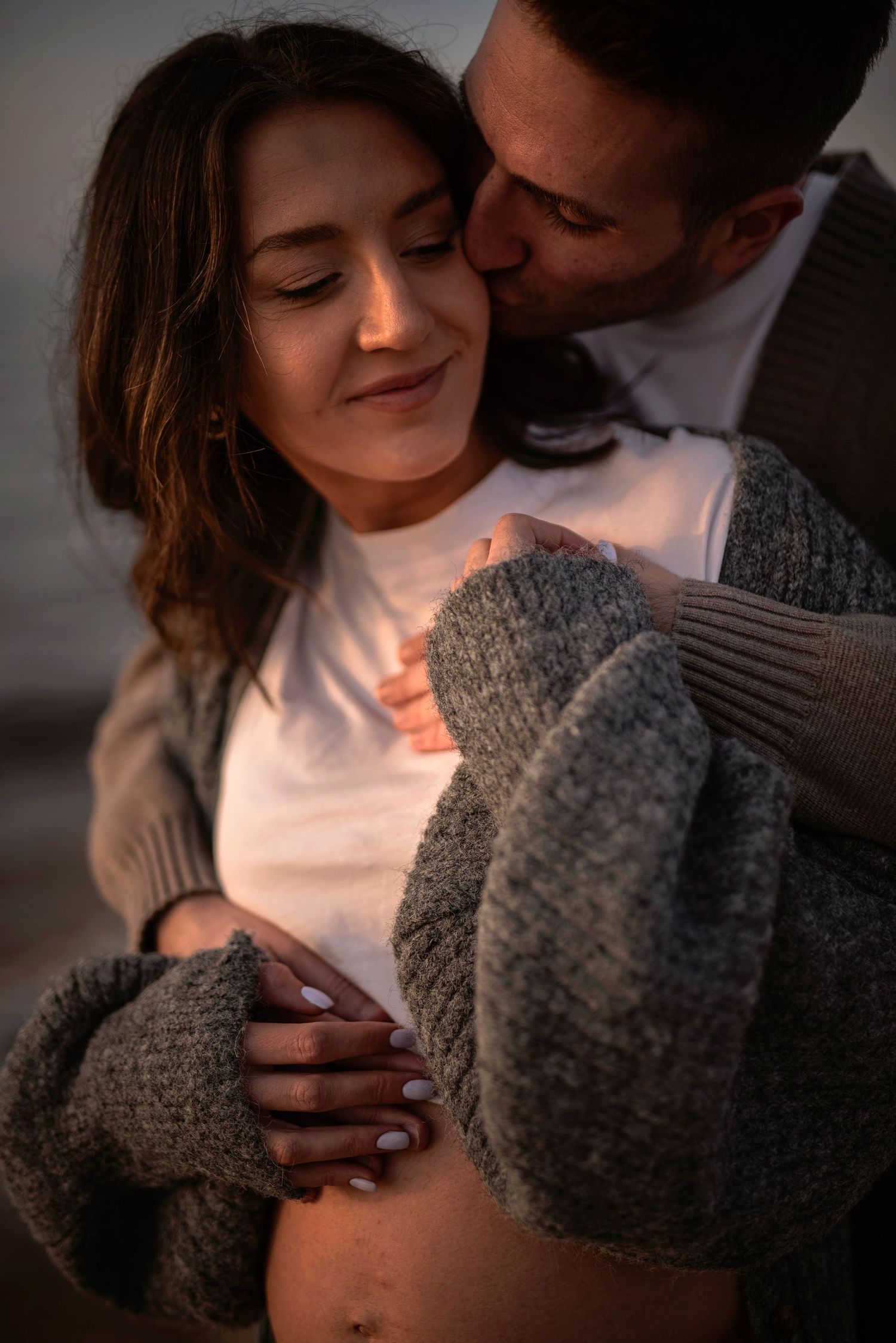 A romantic moment between a couple wearing cozy sweaters captured in warm, intimate lighting.
