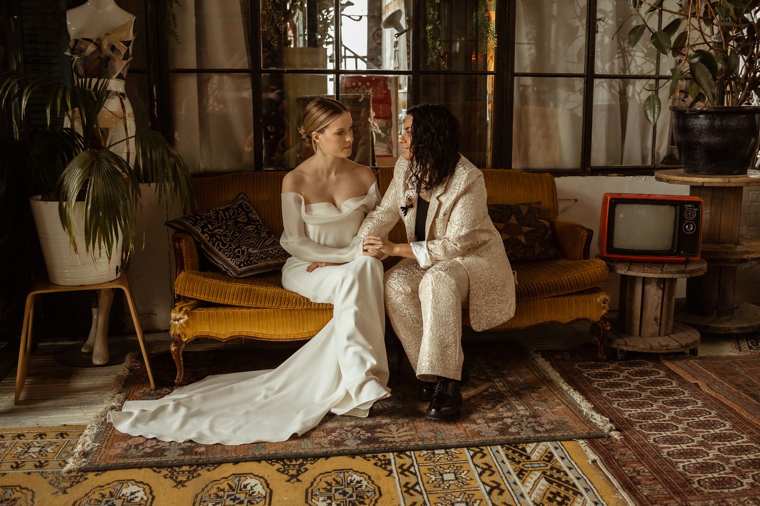 Wedding couple sitting on vintage couch in bohemian styled interior.