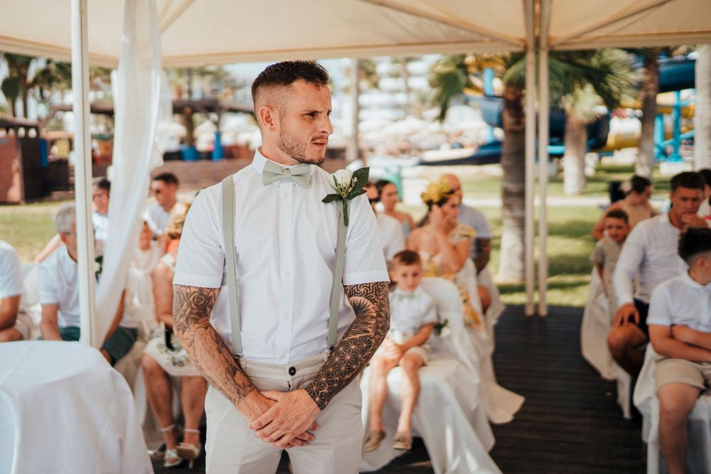 A casual outdoor wedding celebration under a white tent with guests dressed in light summery attire.