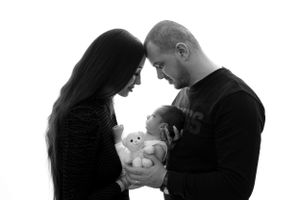 A black and white photograph of a tender moment between parents and their baby.