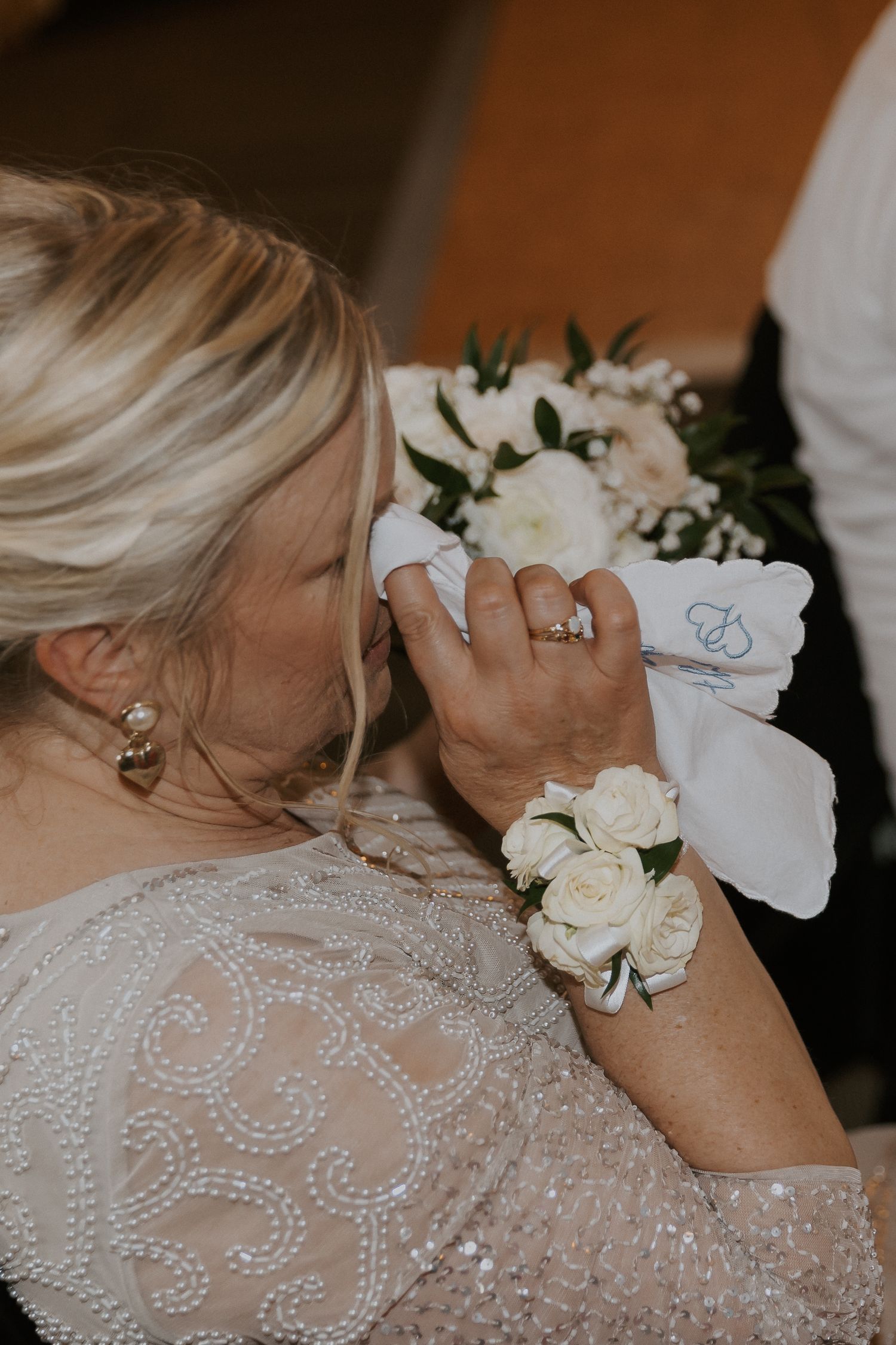 Close-up of bridal corsage with white roses and delicate lace details. Capturing the raw emotion from a luxury wedding.