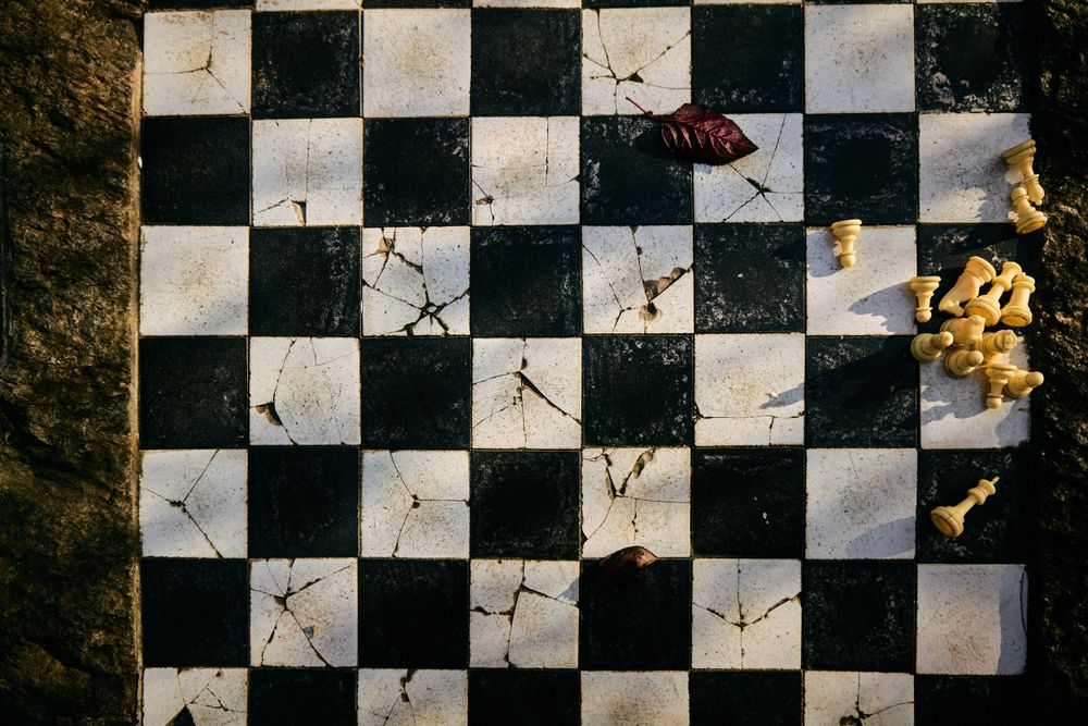 Cracked checkerboard pattern with chess pieces on weathered surface.