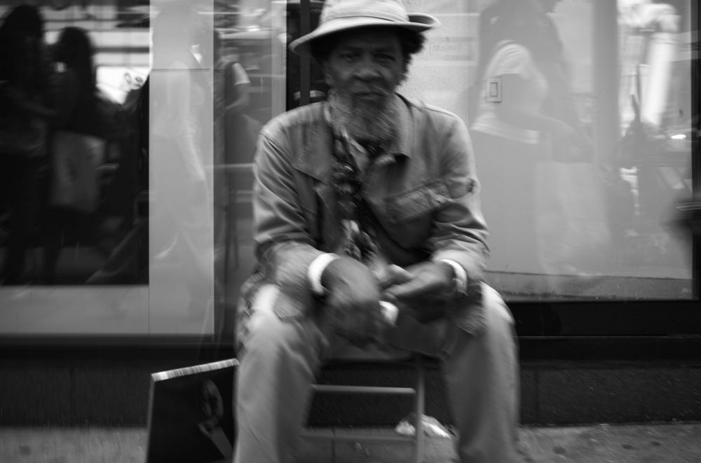 A person sits alone on a bench in a moody black and white photograph.