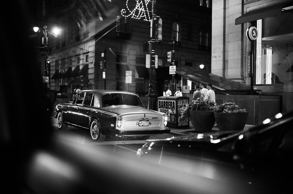 Classic vintage cars parked on a city street at night with street lights glowing.