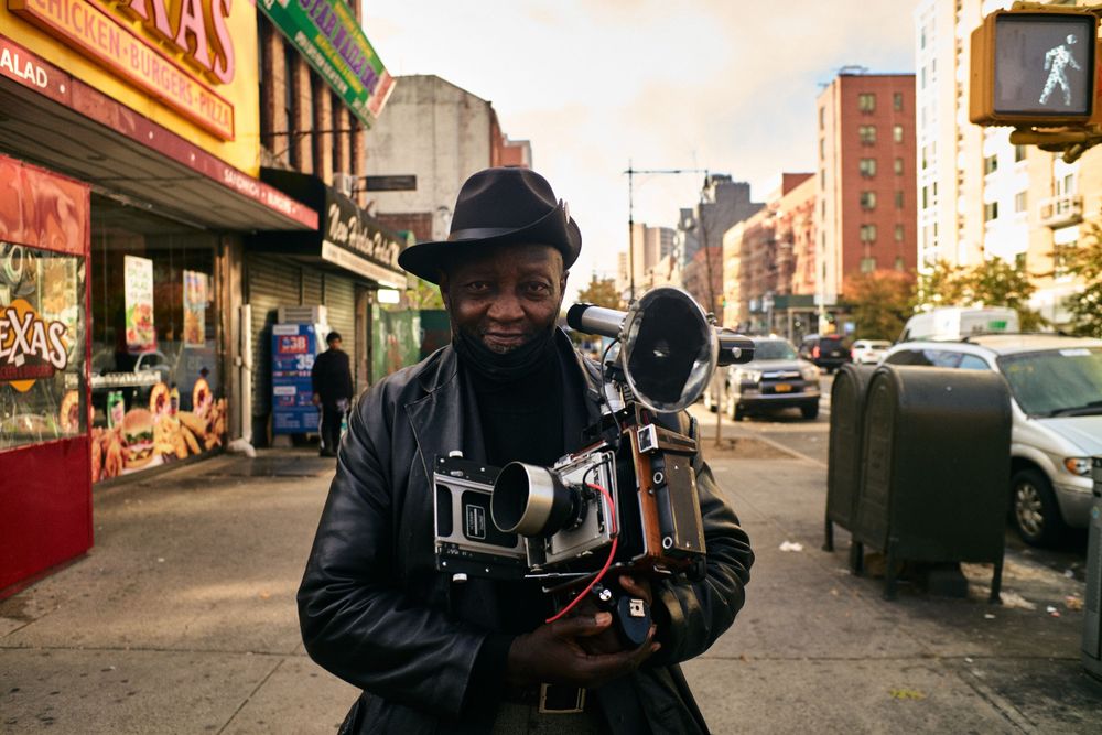 Street photographer with vintage camera on urban sidewalk.