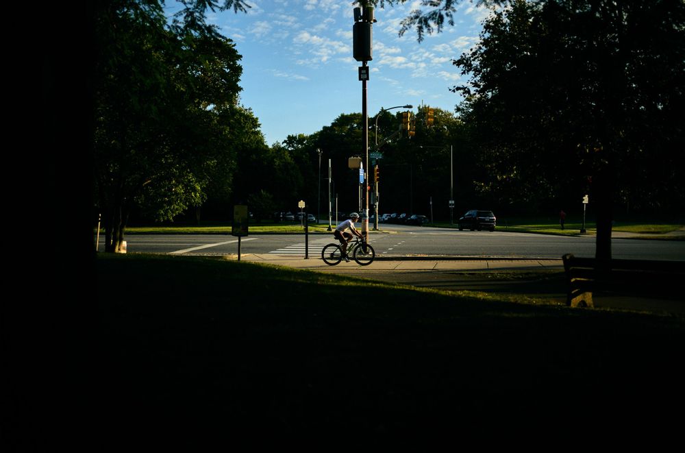 A lone bicycle at intersection in dramatic shadow and sunlight.