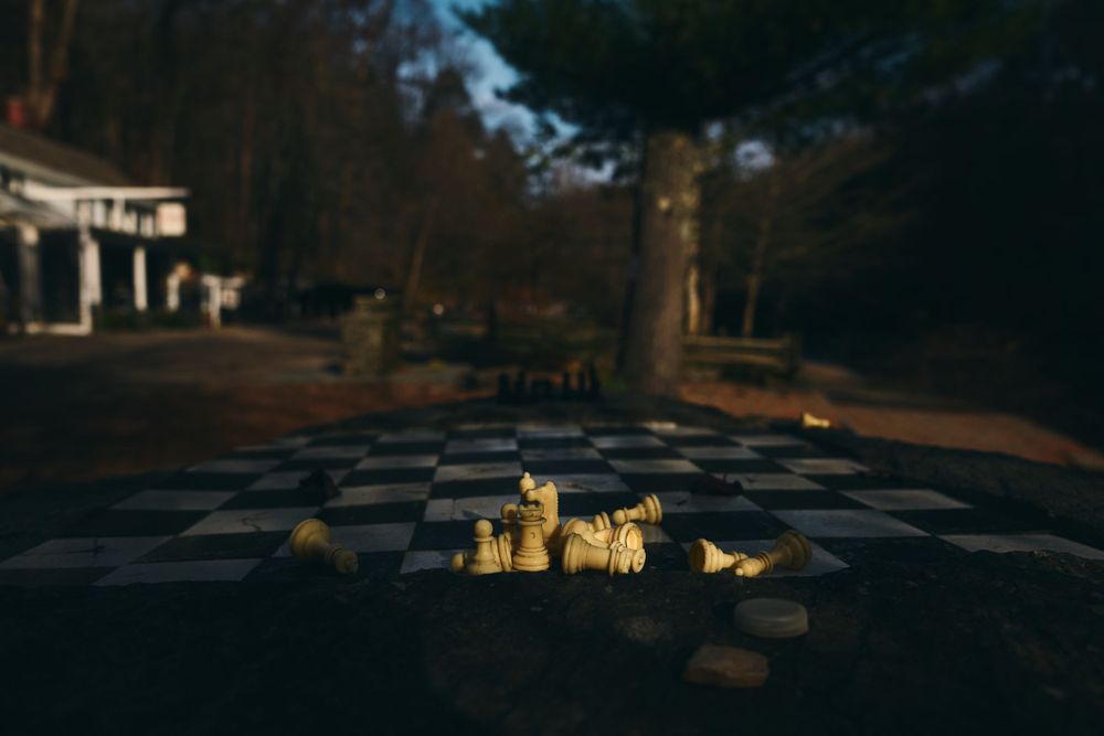Small glowing candles arranged on a checkered surface at dusk.