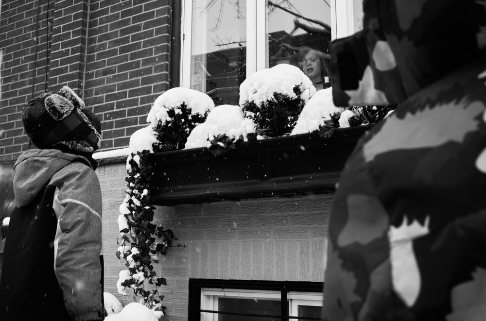 Snow-covered window decorations with onlookers in winter scene.