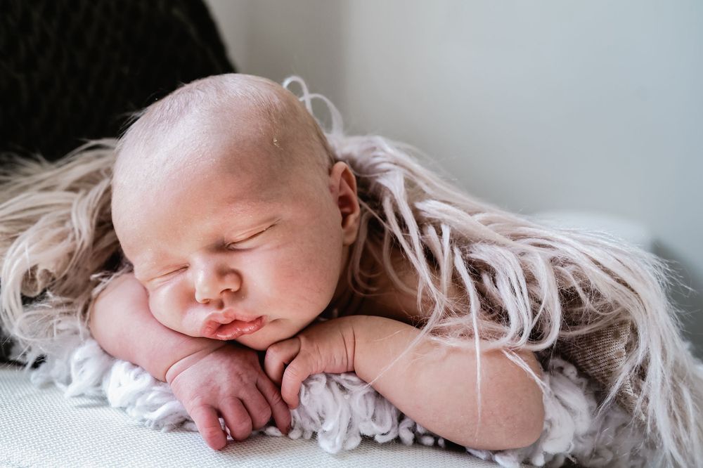 Peaceful sleeping newborn baby resting on textured cream blanket.