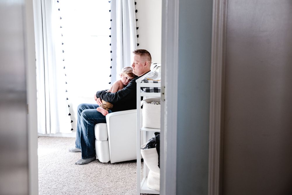 A side view of someone sitting in a white chair near a window.