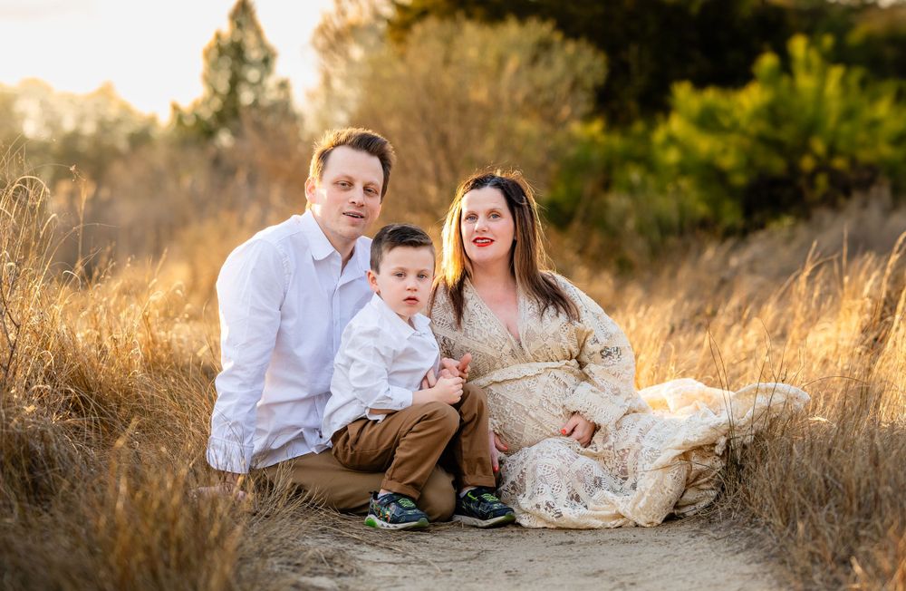 A family sits together in a sun-drenched golden field during a golden hour portrait session.