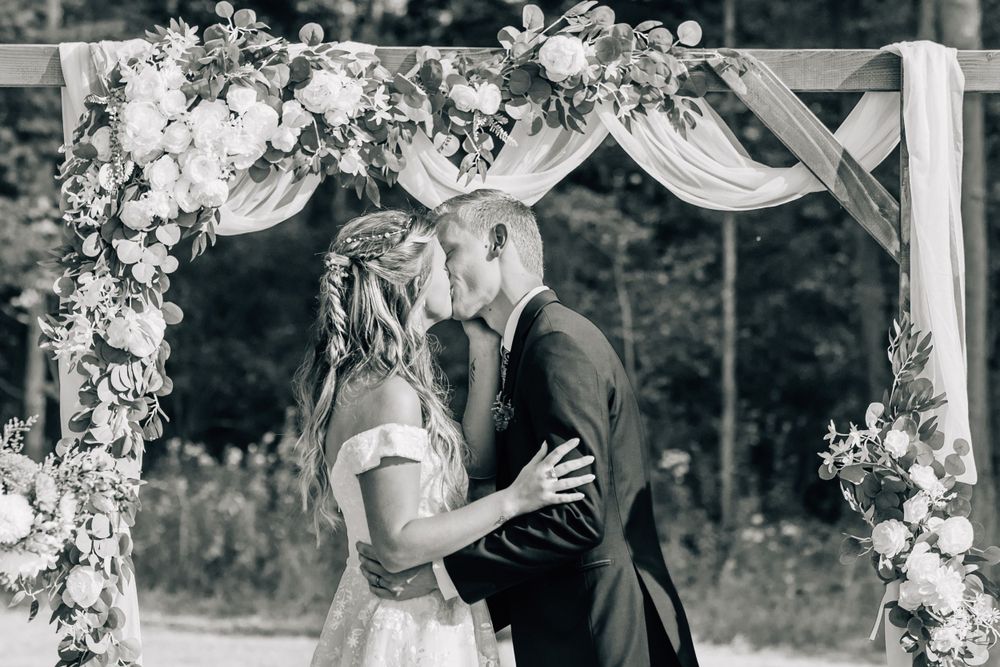 Wedding ceremony arch decorated with white flowers and flowing fabric.