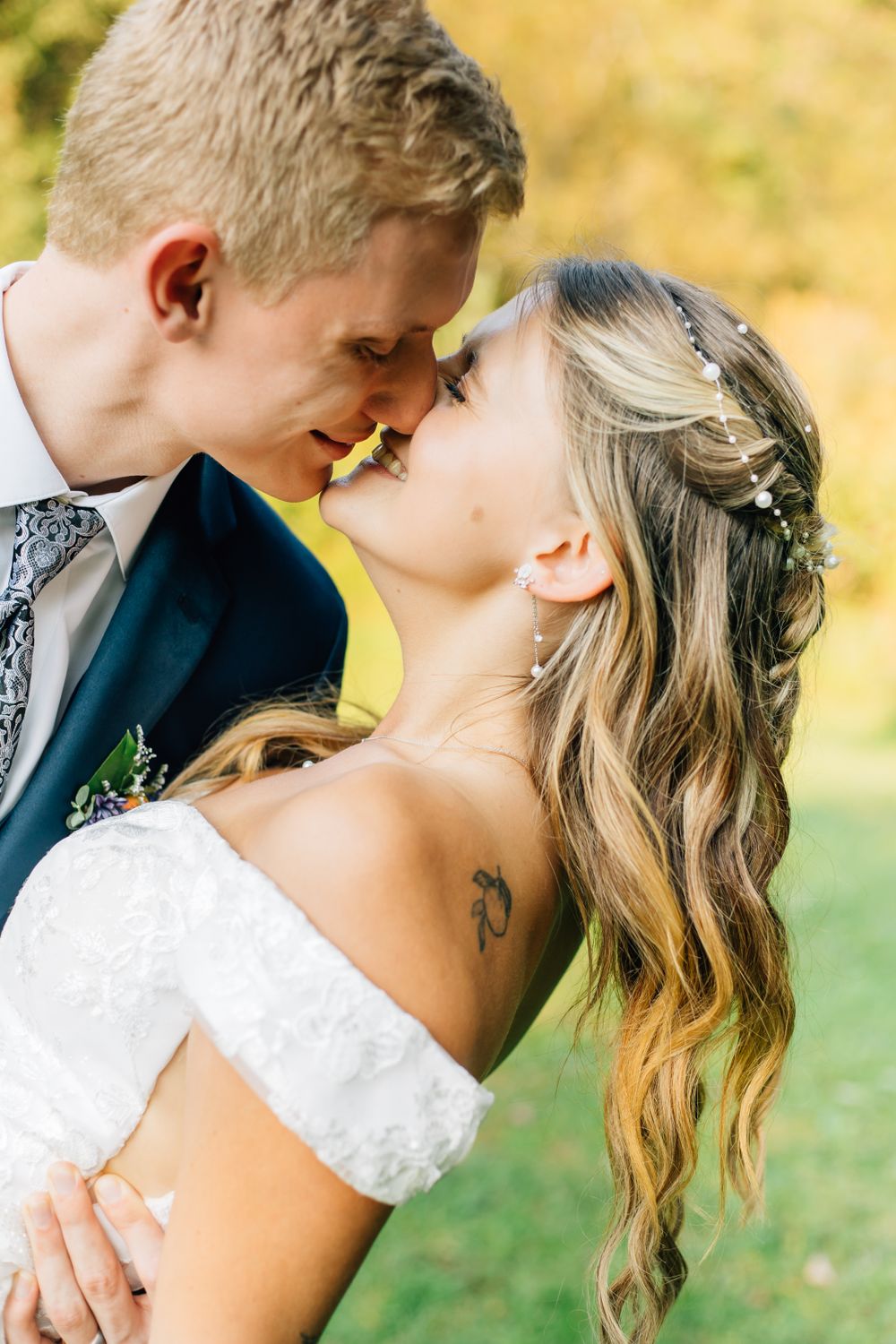 Romantic wedding portrait with couple in white dress and navy suit against fall foliage.
