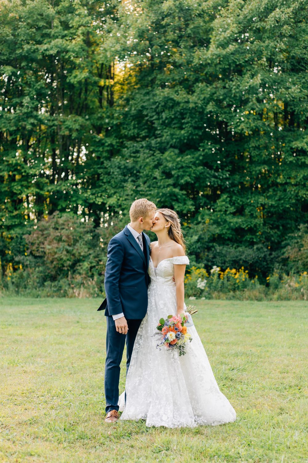 Wedding couple poses in lush green garden setting for romantic portraits.