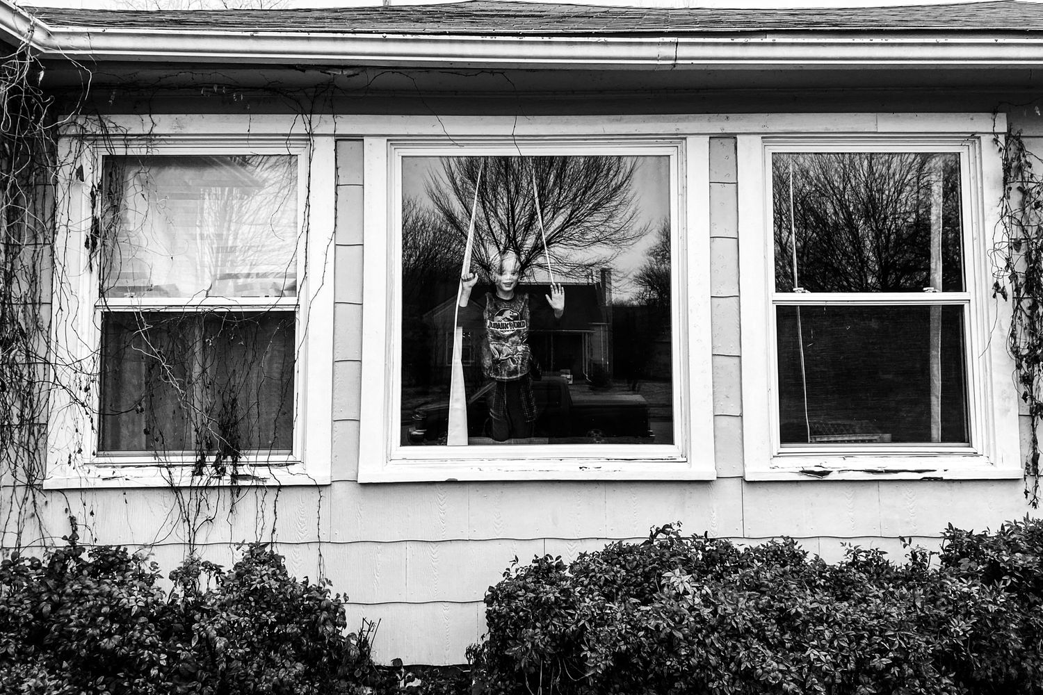 Boy looks out the window in day in the life family photography session in Tulsa, Ok.