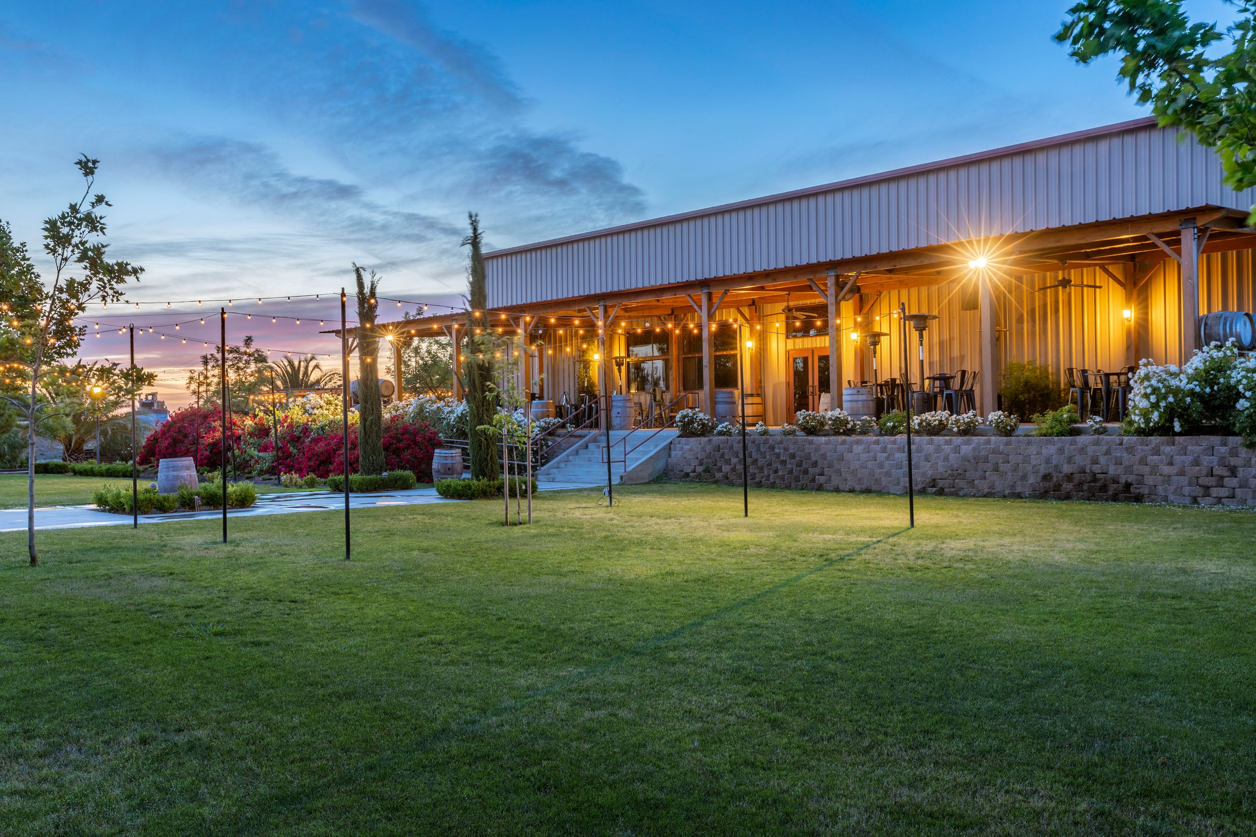 Rustic event venue with wooden exterior and landscaped grounds at sunset.