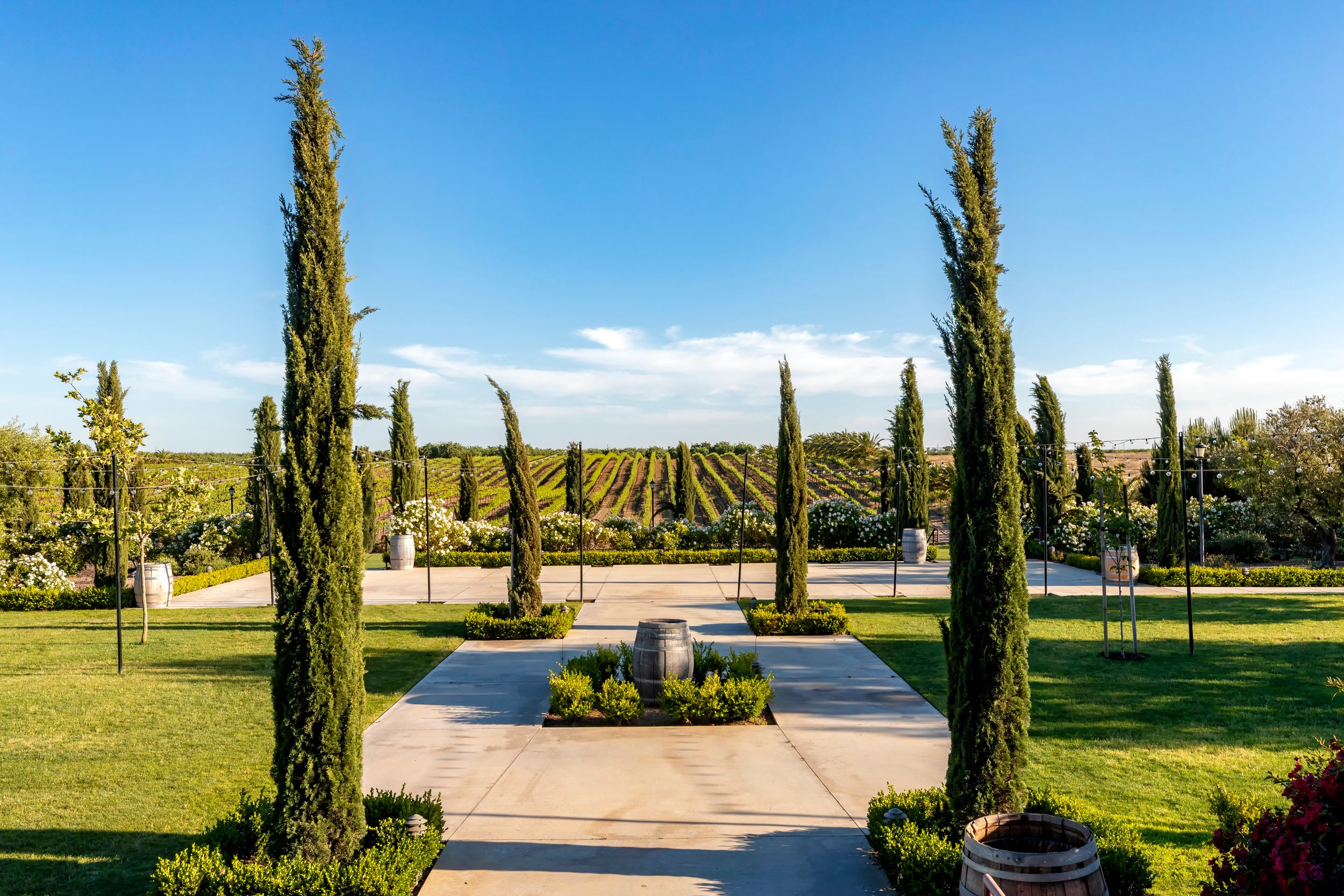 Symmetrical garden path lined with tall cypress trees leading to a central fountain.
