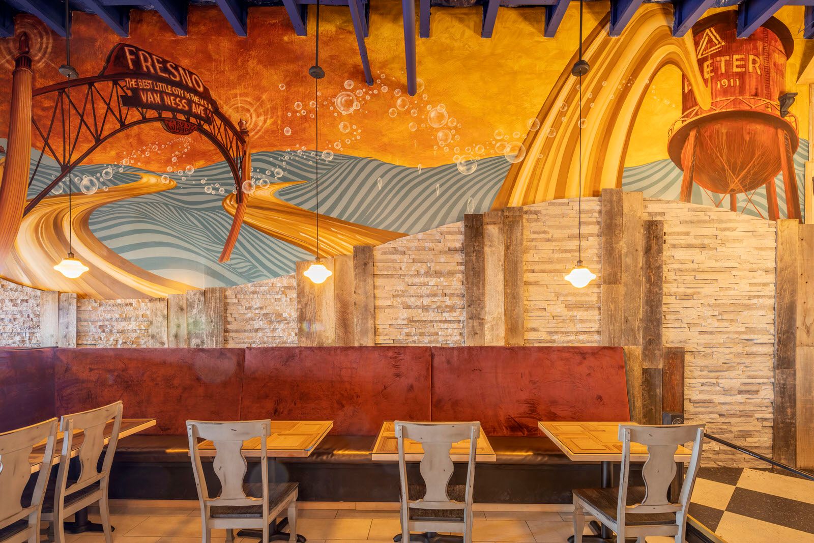Restaurant dining area with vibrant orange mural walls and contemporary seating arrangement.