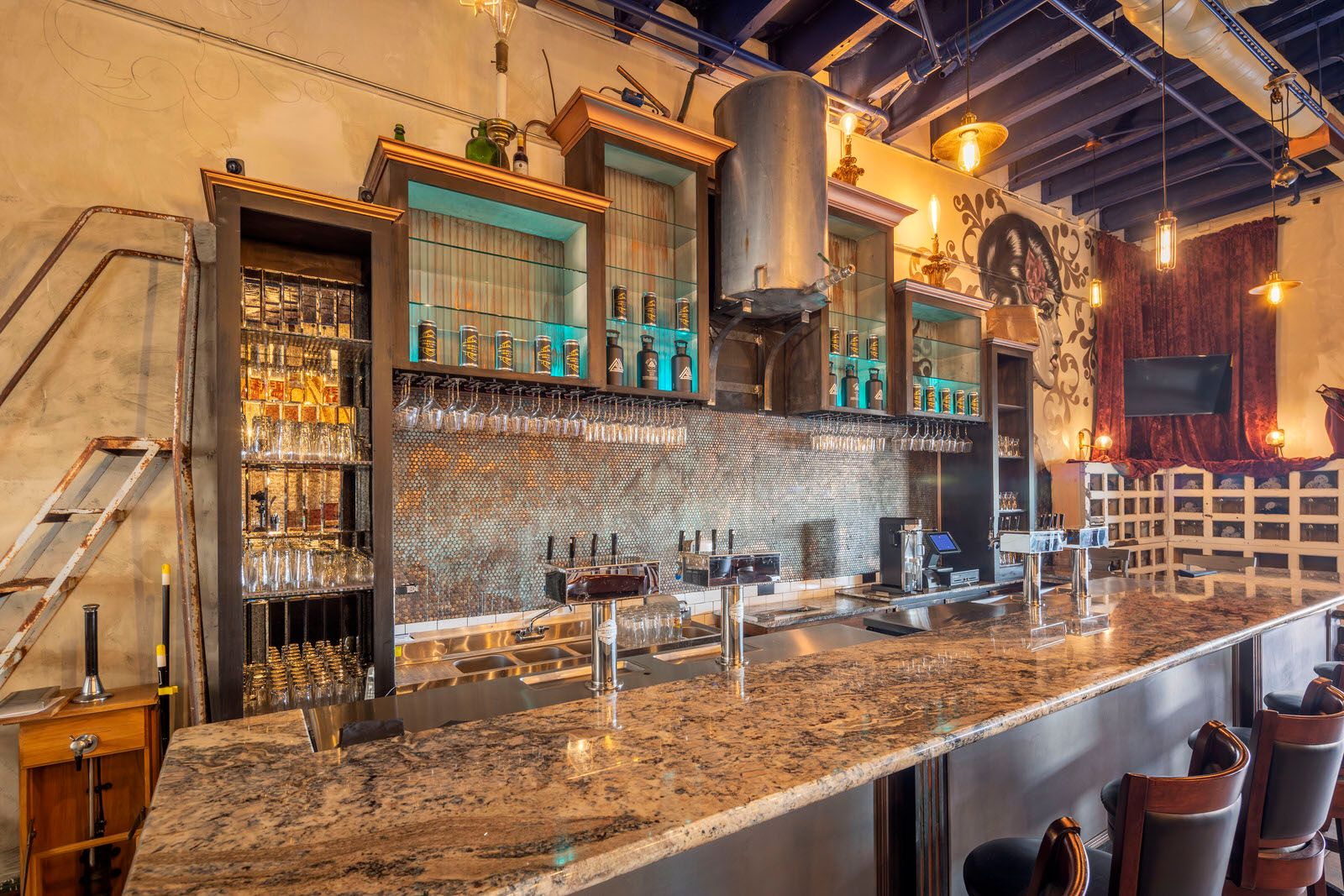Modern bar interior with marble countertop, glass shelving, and industrial-style lighting fixtures.