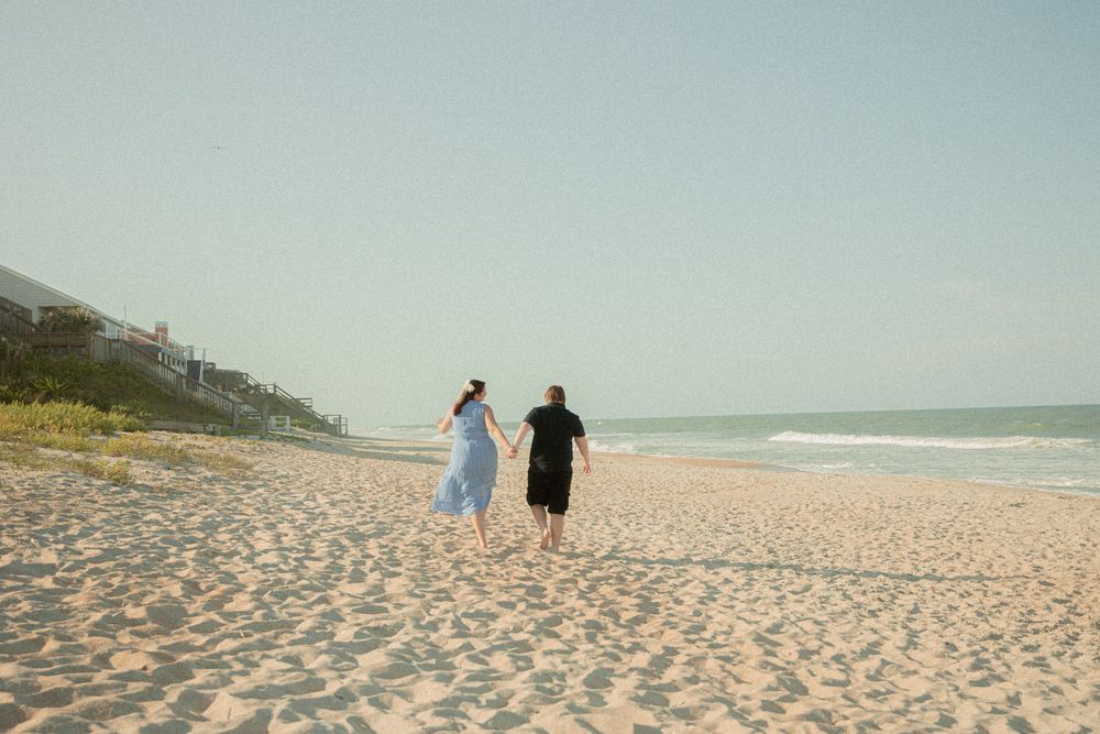 Panoramic view of people walking along a pristine sandy beach with blue ocean waves.