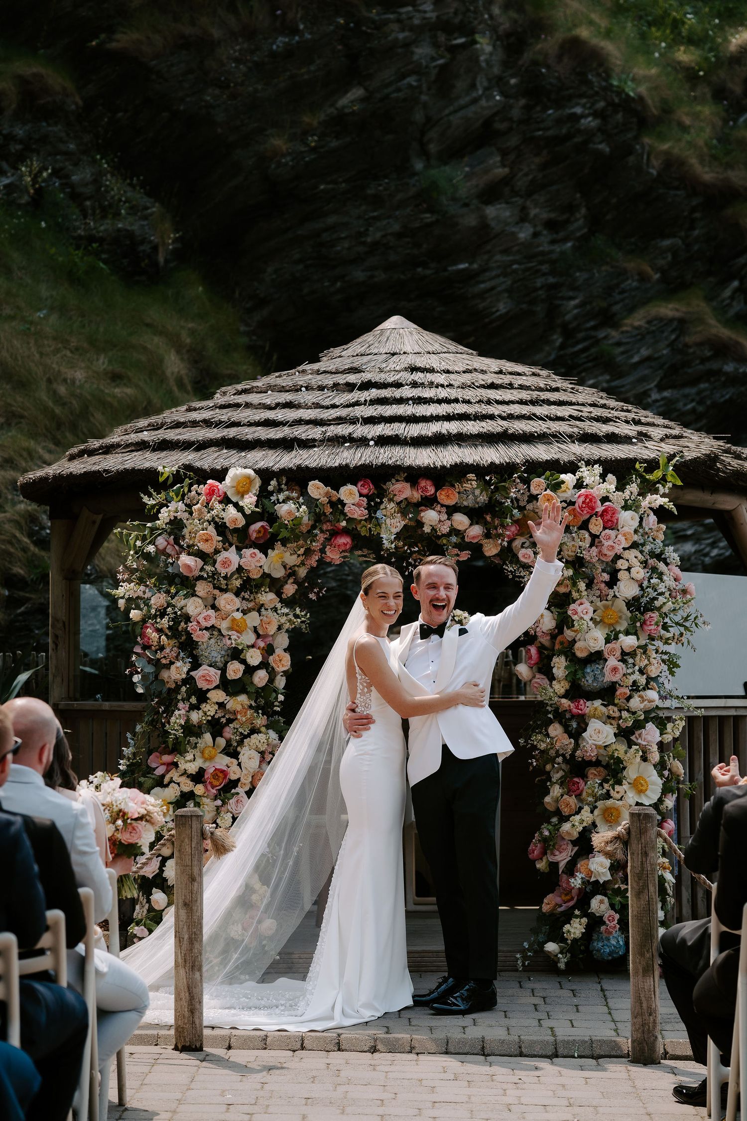 Bride and Groom in front of floral arch next to the sea at Tunnels Beach Wedding Venue in North Devon