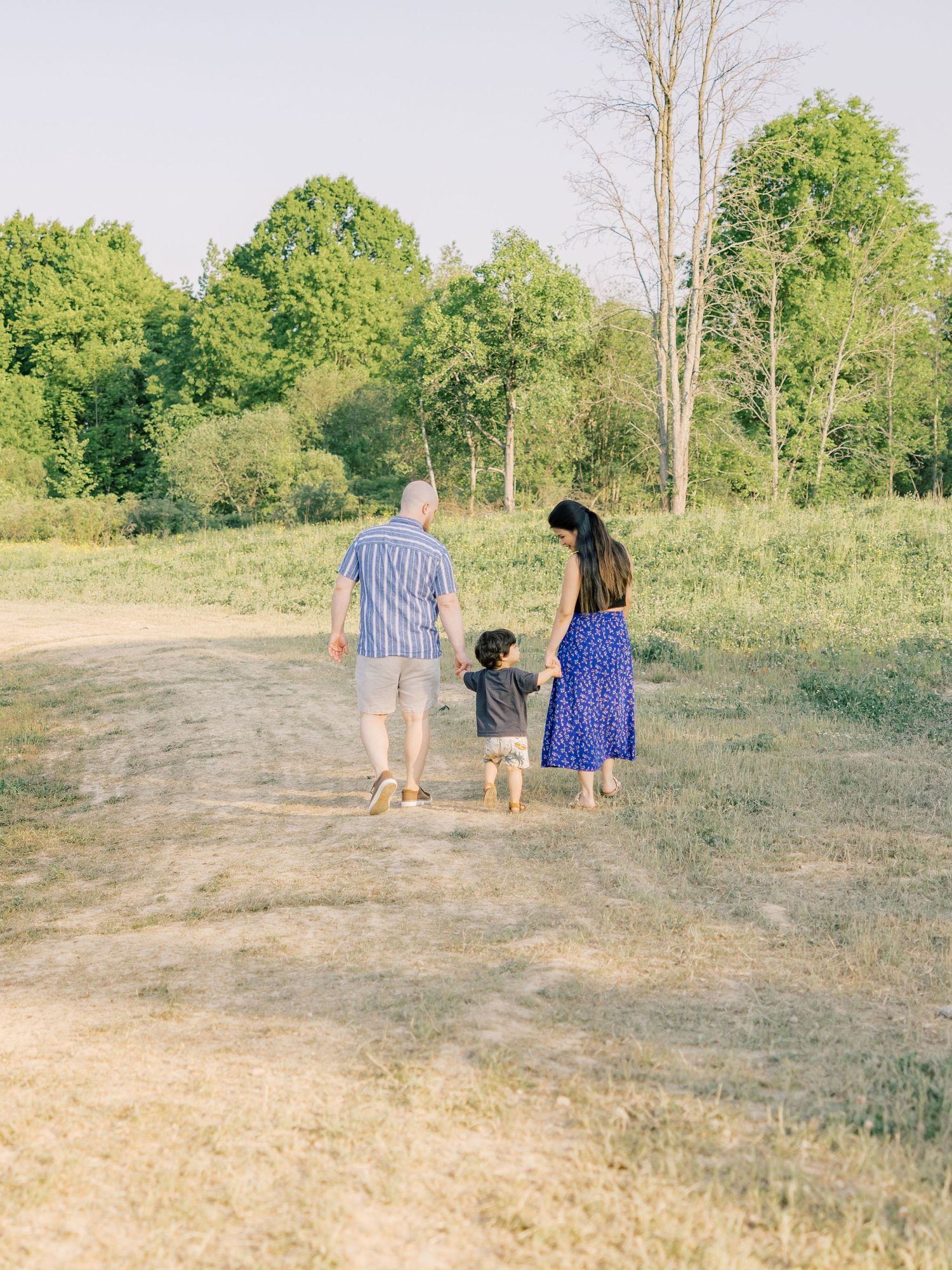 A group walking together on a dirt path through a lush green field on a sunny summer day.