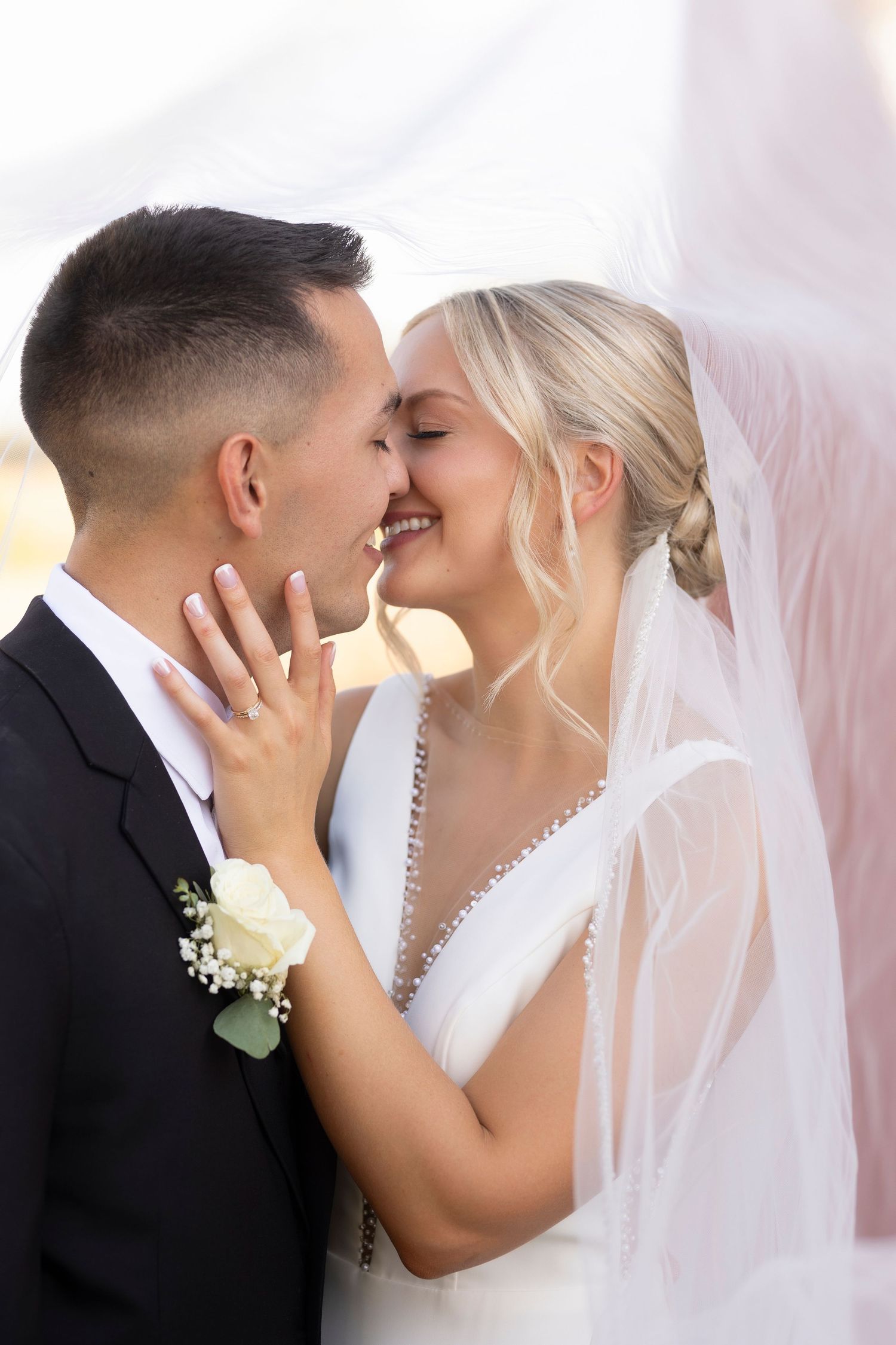 Intimate wedding portrait with flowing veil and white floral boutonniere.