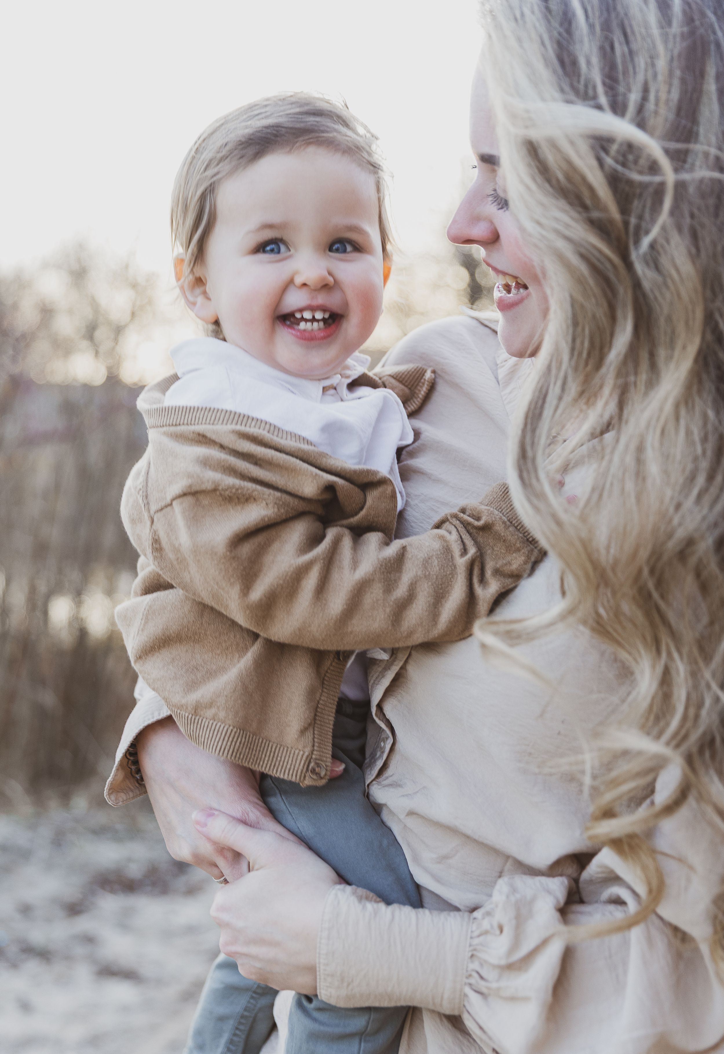 Joyful moment shared between parent and child wearing matching neutral tones. Moeder en zoon fotografie.