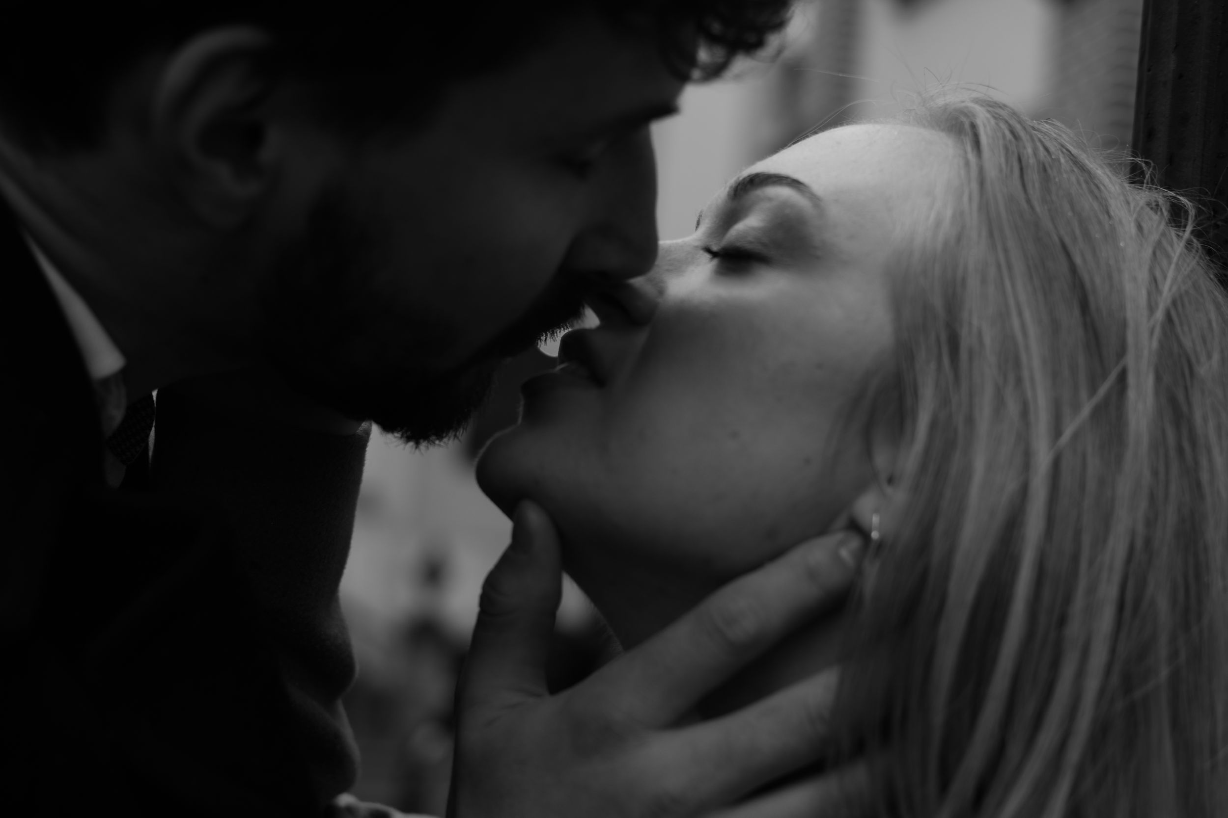 A romantic black and white close-up shot of a couple sharing an intimate kiss.