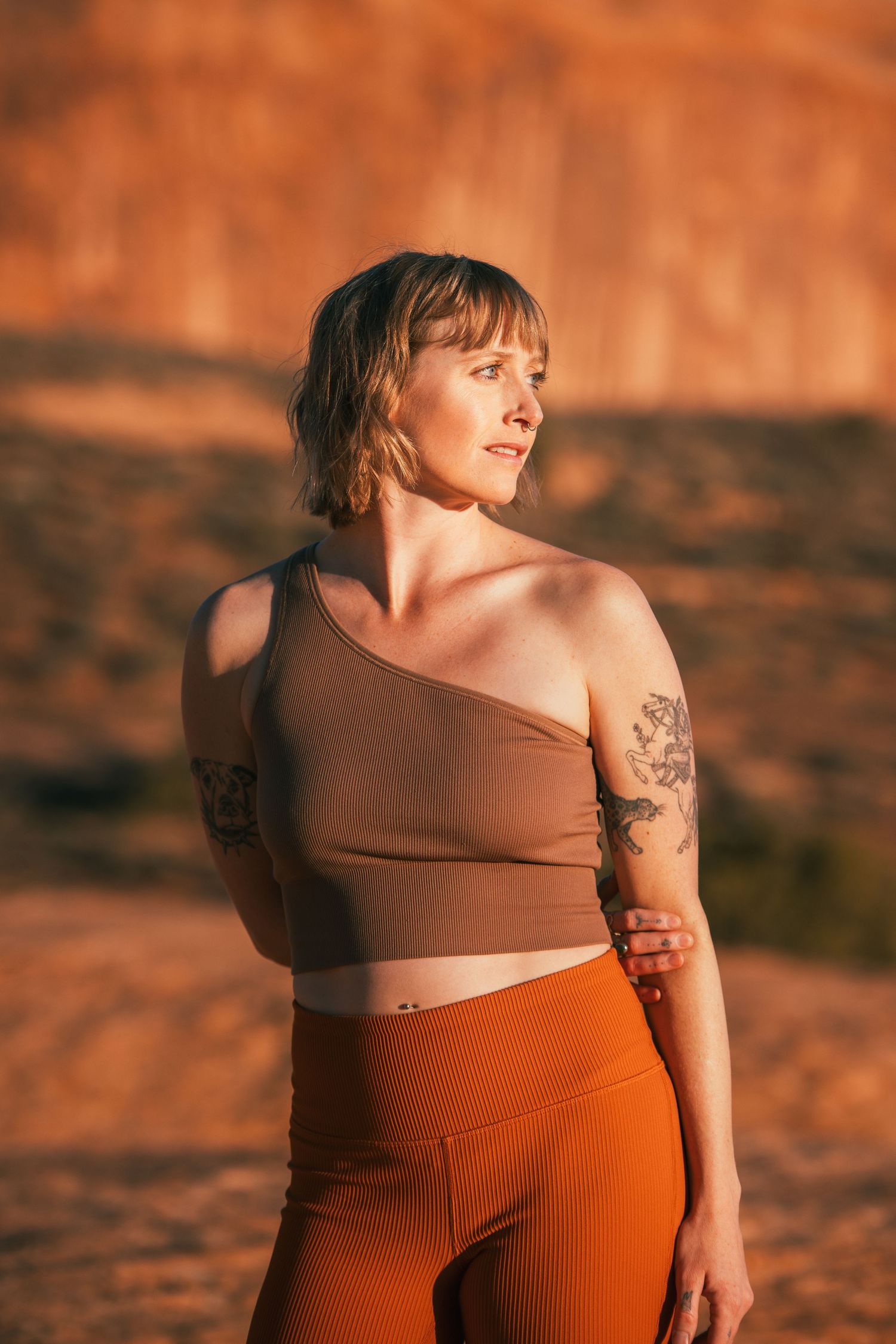 Portrait of person in athletic wear posing against red rock formations at sunset.