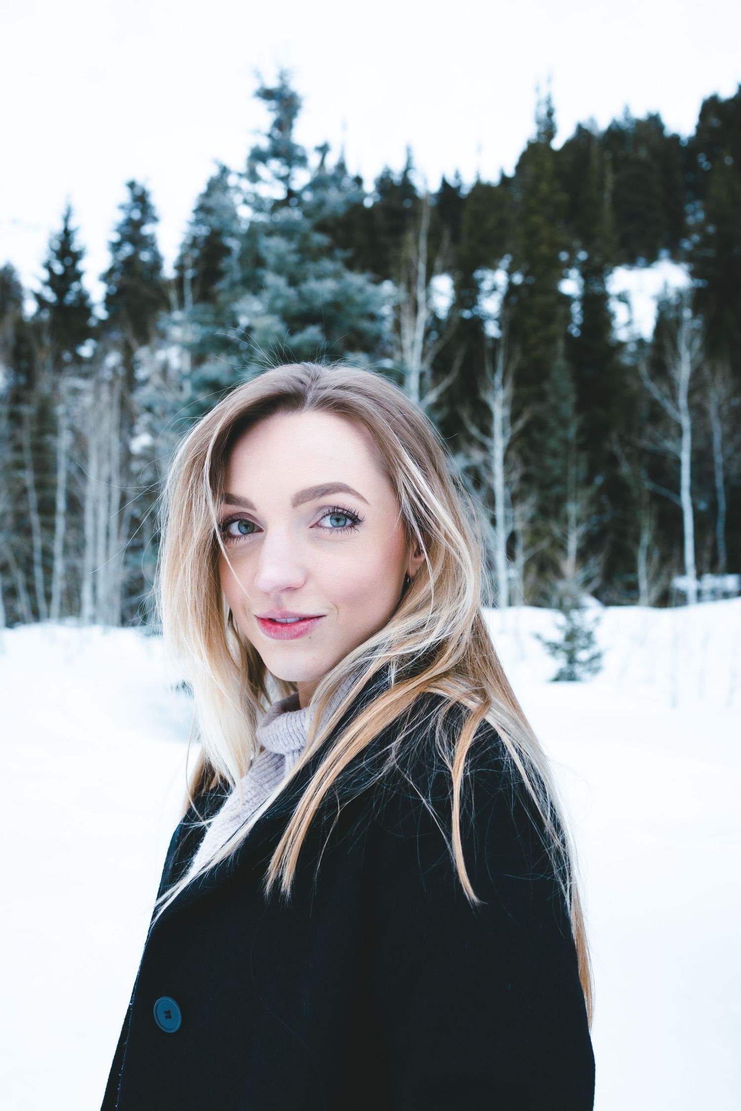 Winter portrait against snowy forest backdrop with evergreen trees and white aspens.