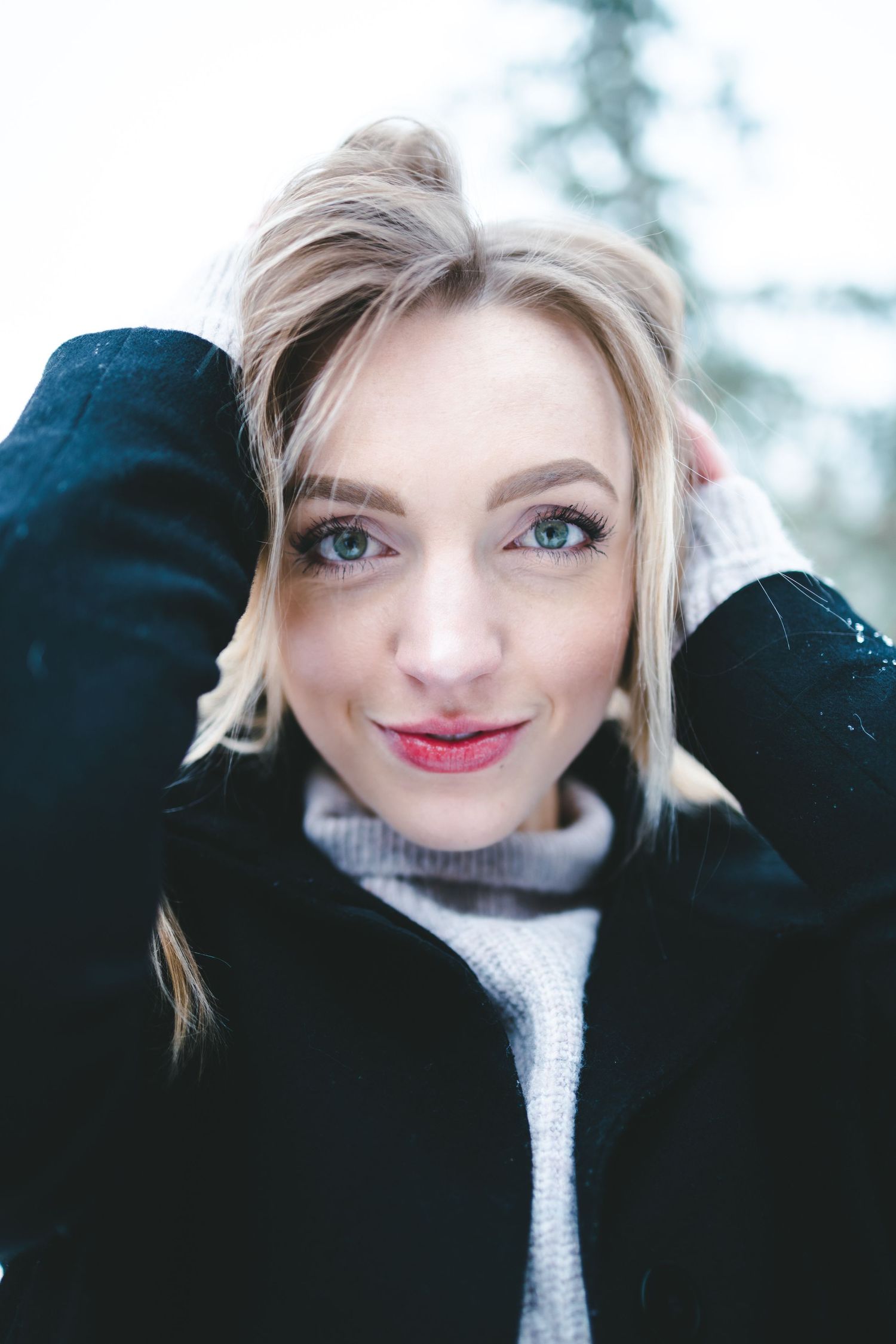 Close-up winter portrait featuring a white knit sweater and black coat.