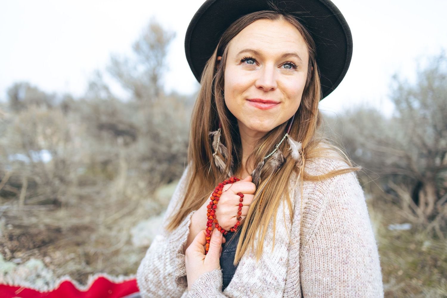 Portrait in neutral tones wearing a wide-brimmed hat and cream colored sweater.