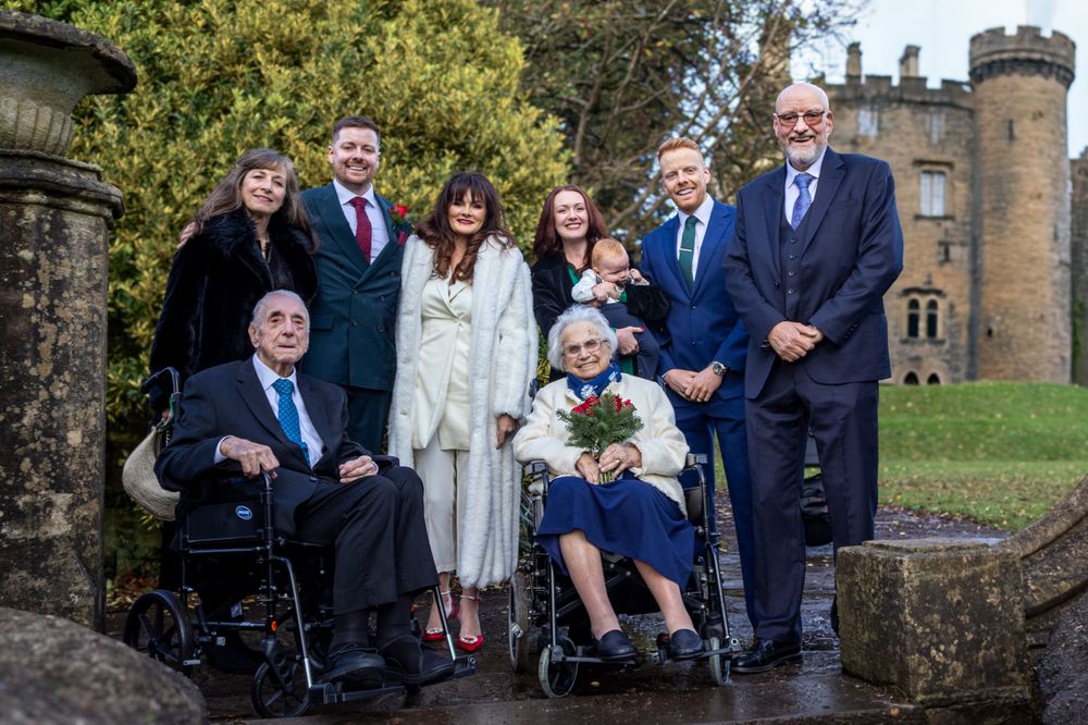 A family group poses for a formal photo outside a castle.