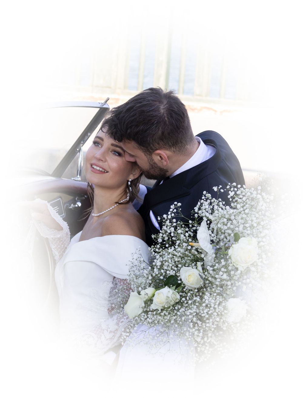 A romantic wedding photo with white roses and baby's breath flowers against a soft-focused vignette background.