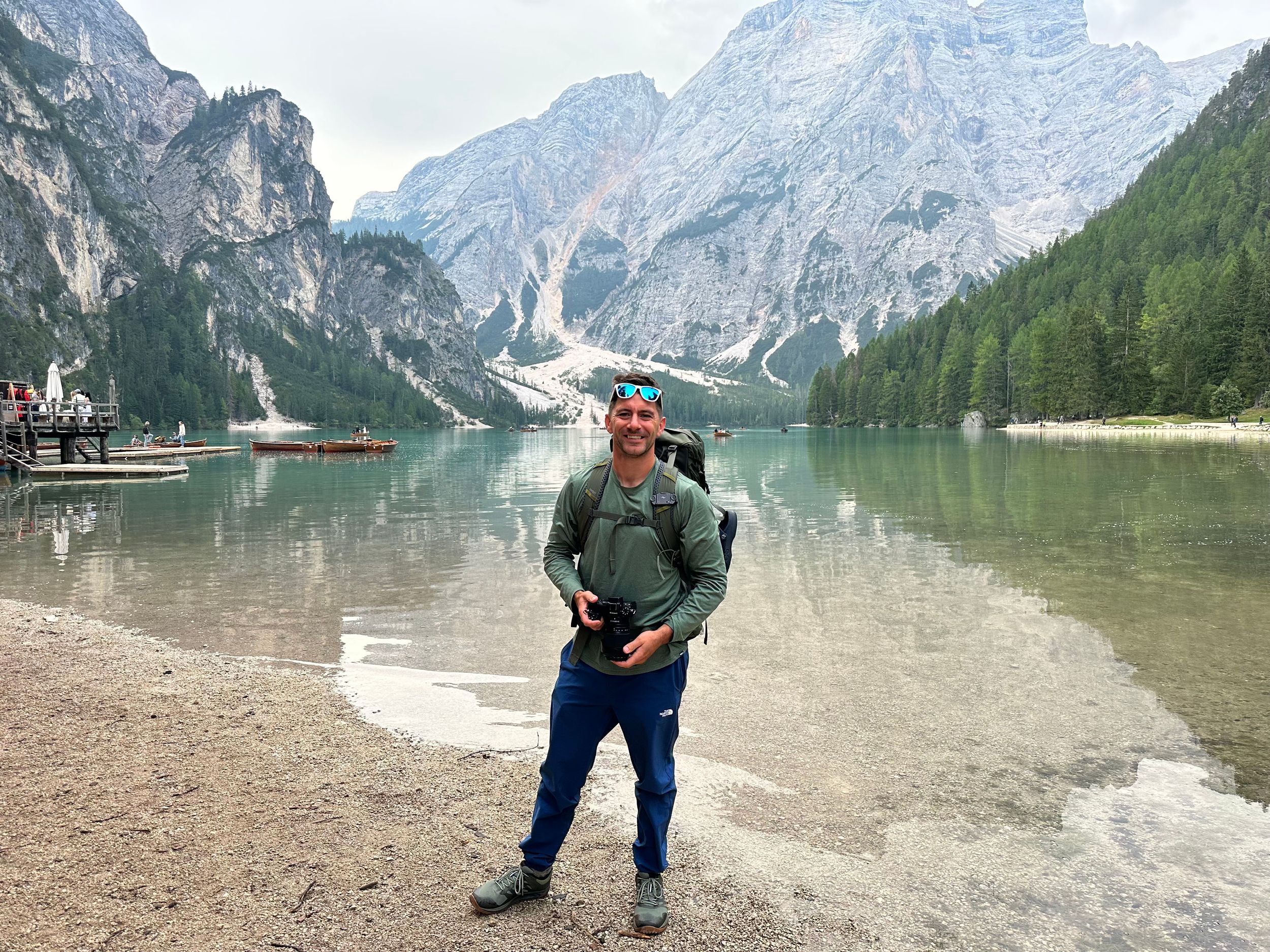 Panoramic view of a pristine alpine lake surrounded by towering mountain peaks and dense forest.